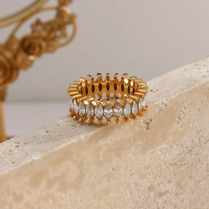 Close-up of golden zircon ring with marquise stones on beige marble surface