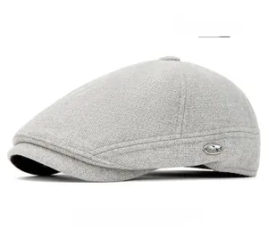 Detail of light gray wool flat cap showing the fine texture and oval metal brand emblem
