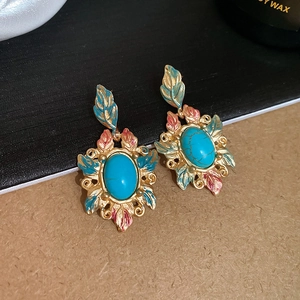 Detailed view of vintage metal earrings with turquoise gems and colorful enamel leaves