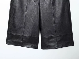 Detail shot of black faux leather shorts showing fine texture and quality stitching