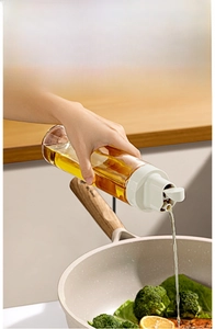 Detail of gravity sensor oil dispenser pouring into a pan with fresh broccoli