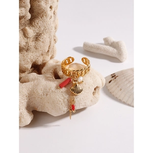 Detailed shot of a gold ocean style ring with shell and pearl charms on white coral