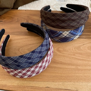 Detail view of retro plaid wide headbands in red, blue, and coffee fabric on wood