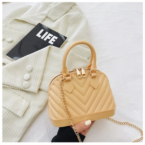 Close-up of cream beige shell jelly bag with V-textured surface and gold chain strap