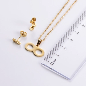 Infinity pendant necklace and earrings set shown with a ruler for size reference
