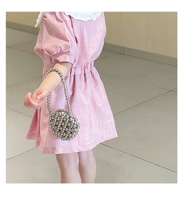 Close-up of pink linen dress paired with a silver metallic beaded crossbody bag for kids