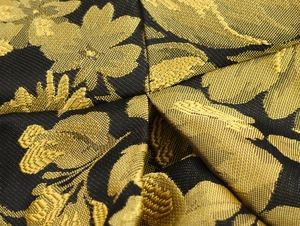 Detalle macro de la elegante tela de brocado jacquard negro y dorado con flores