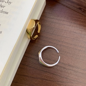 Detail view of gold and silver S925 minimalist wide band rings on a wooden table