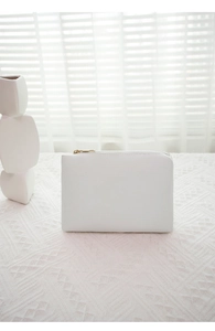 Close-up of white minimalist embroidered inner pouch with gold zipper detail