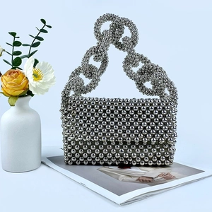 Macro shot of silver beaded evening bag featuring metallic chain handle and flap closure