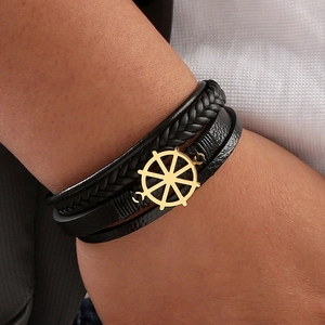 Close-up of men's leather nautical bracelet with a polished golden ship wheel charm