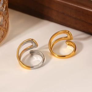 Macro detail of bicolored and gold irregular curved rings on warm white surface