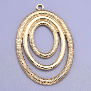 Detailed macro of gold oval pendant with textured concentric rope rings and small top loop