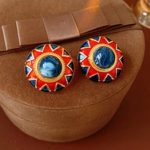 Macro detail of vintage round enamel earrings with blue gemstones in a jewelry box