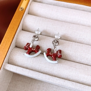 Detailed shot of silver rocking horse earrings with red enamel and zircon stones