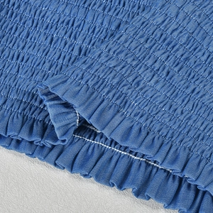 Detailed view of blue smocked fabric with ruffled edges and fine stitching texture