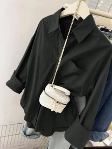 Détail d'une chemise noire à manches longues avec un mini sac matelassé blanc à chaîne
