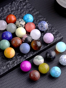 Macro view of polished 16mm natural crystal balls and gemstones on dark textured slate