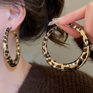 Close-up detail of oversized gold hoop earring featuring classic leopard print pattern