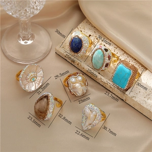 Flat lay of vintage gemstone rings with mother of pearl and turquoise on satin