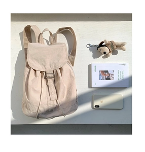 Detailed top view of beige nylon backpack with metal buckles and stylish lifestyle props