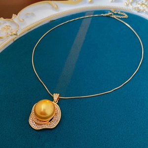 Detailed macro view of a vintage gold necklace with a large golden pearl and zircon pendant