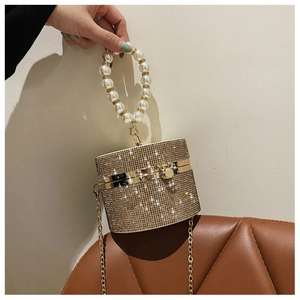 Detailed view of luxury gold cylindrical evening bag with rhinestones and pearl handle