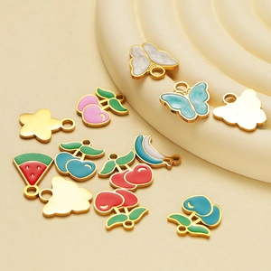 Golden stainless steel enamel fruit and shape charms collection on beige surface