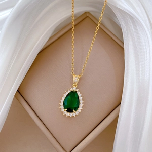 Close-up of a gold teardrop necklace with green zircon in an elegant jewelry box