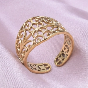 Vue détaillée d'une bague dorée à motif floral sur soie, montrant la texture brossée vintage