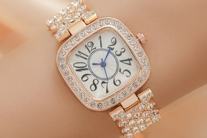 Gros plan d'une montre carrée en or rose pour femme avec aiguilles bleues et strass