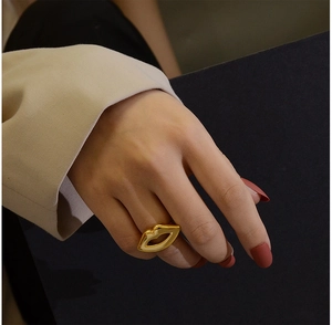 Detail shot of a creative 18K gold-plated lip-shaped ring on a hand with red nails