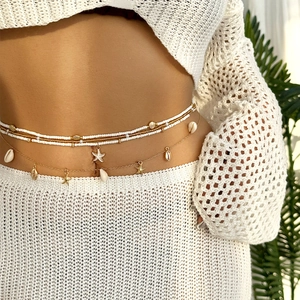 Detail of layered waist chain with white beads, golden starfish and shell charms