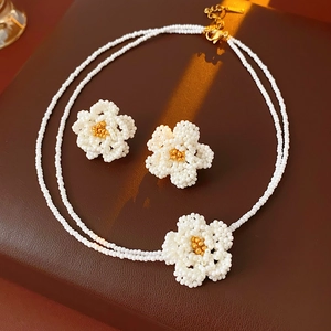 Detailed close-up of beaded camellia flower necklace and earring set on leather