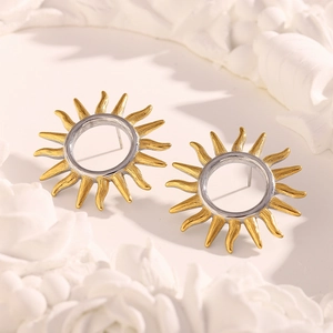 Detail of 18K gold-plated hollow sun stud earrings on a textured white relief backdrop