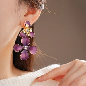 Detail of purple enamel flower earrings with gold edges and crystal centers on model