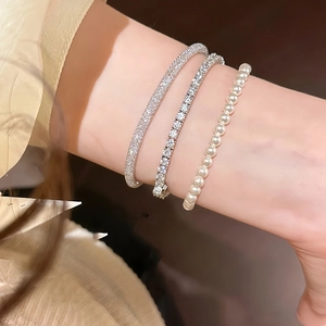 Set of three luxury bracelets featuring tennis zircon, pavé stones and white pearls on wrist