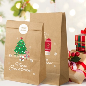 Close-up of brown kraft Christmas gift bags with festive tree prints and Merry Christmas text