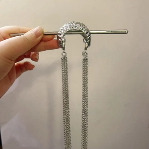 Detailed view of silver hair pin with hammered metal texture and long tassel chain