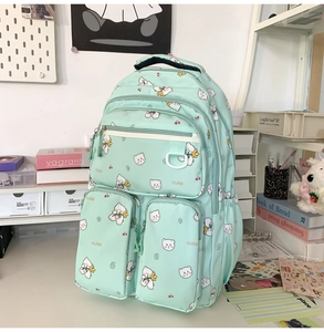 Close-up of light green multi-pocket backpack with cute bear pattern and textile texture