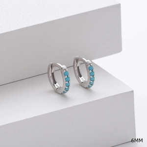 Close-up of 6mm 925 sterling silver hoop earrings with inlaid turquoise on white stand