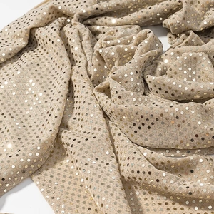 Détail macro de paillettes dorées champagne sur un tissu scintillant pour robe de soirée