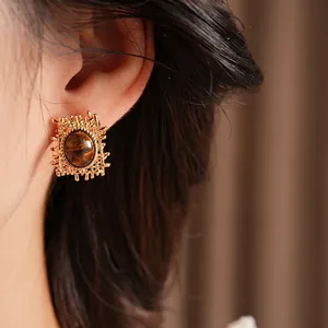 Retro gold earrings with oval tiger eye stones in vintage metallic lava style on model