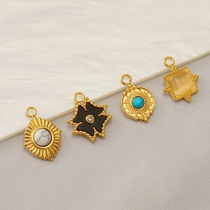 Golden stainless steel pendants set with marble, turquoise, and opal on white background
