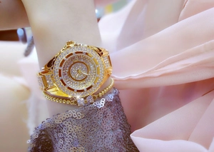 Close-up of luxury gold women's watch with rhinestones and matching bead bracelet