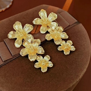Macro view of vintage golden triple flower drop earrings on a brown velvet jewelry box