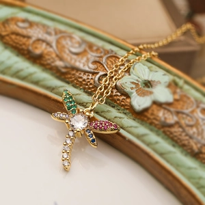Macro shot of a gold-plated dragonfly pendant set with colorful vibrant zircons