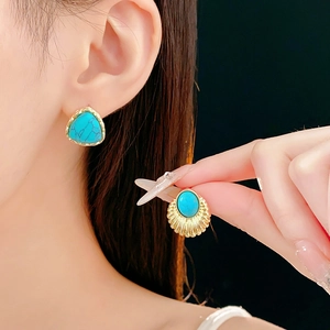 Detail of vintage gold earrings with green turquoise stones in drop and shell shapes