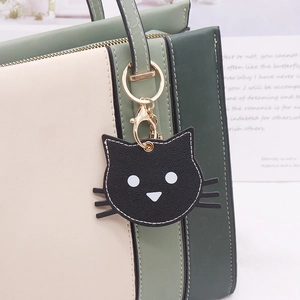 Cute black cat PU leather keychain pendant with gold metal ring on a stylish handbag