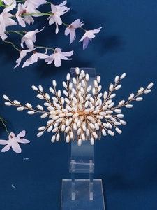Detailed close-up of handmade bridal hair comb with pearls and golden wire leaves
